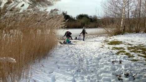 Children-sledding-across-the-ice-on-a-frozen-pond-in-a-city-park-during-the-freezing-cold-in-February,-which-lasted-only-one-week-in-the-Netherlands-in-2021