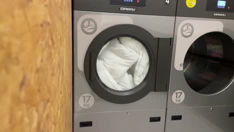 Front-view-of-tumble-dryer-operating-with-white-bed-quilt-inside