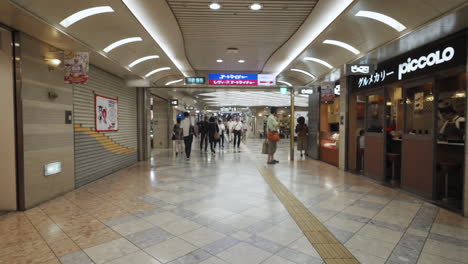 Pedestrians-in-the-Namba-Walk,-an-underground-corridor-between-subway-stations-lined-with-eateries-and-stores,-in-Osaka-Japan,-wide-dolly-in-slow-motion