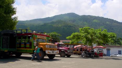 Klassische-LKW-Busse-Parken-Vor-Einem-Berg-Auf-Einem-Marktparkplatz-In-Valparaíso,-Kolumbien