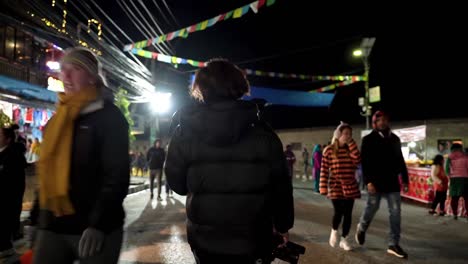 Back-view-of-a-young-photographer-walking-in-the-street-with-his-camera-during-the-21st-street-festival-Pokhara