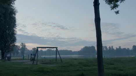 Walking-past-a-playground-next-to-a-lake-in-the-early-morning