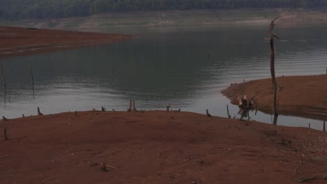 Tilting-down-shot-of-mountain-range-and-a-lake-with-small-isles-and-an-old-abandoned-white-fishing-net-on-the-water-edge