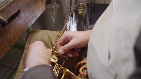 Skilled-instrument-maker-repairing-keys-of-golden-saxophone-body-by-hand