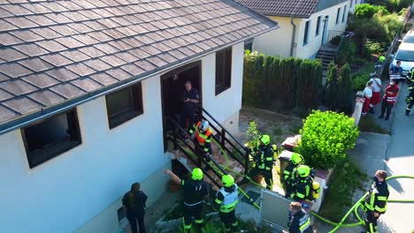 AERIAL---Firefighters-outside-a-house-in-Oberwaltersdorf,-Austria,-wide-shot