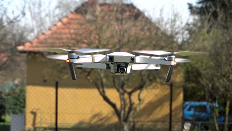 Close-up-front-view-of-a-white-quadcopter-drone-flying-in-the-breeze,-real-time