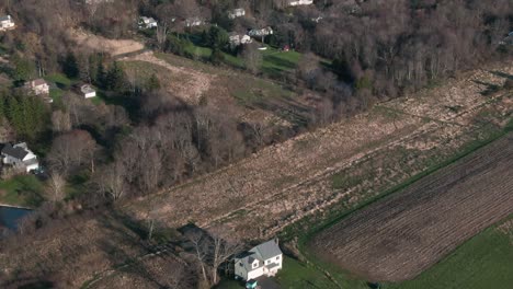 Paisaje-Rural-Con-Bosques-Caducifolios-Y-Varias-Fincas-Agrícolas,-Inclinación-Aérea-Hacia-Arriba