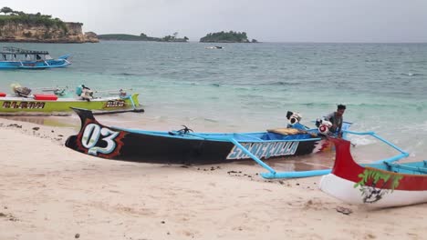 Ein-Fischerboot,-Das-Von-Einem-Fischer-Gesteuert-Wird,-Der-Am-Pink-Beach-In-Lombok,-Indonesien-An-Land-Kommt---Schwenkaufnahme