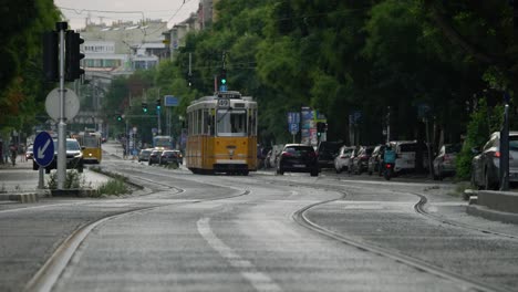 Ruhige-Teleaufnahmen-Einer-Alten-Gelben-Straßenbahn,-Die-In-Budapest-Beschleunigt