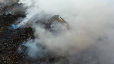 Aerial-view-of-a-excavator-and-firemen-trying-to-extinguish-a-wildfire,-white-smoke-rising,-cloudy-day,-in-Amazon,-Brazil,-South-America---Static,-drone-shot