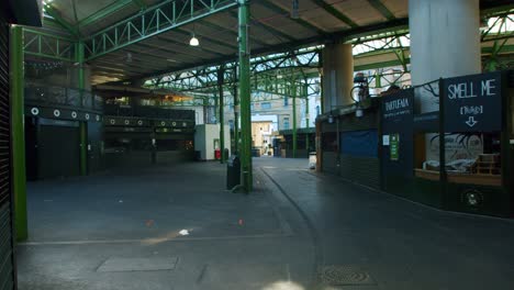 Lockdown-in-London,-cinematic-lens-flare-reveal-of-empty-Borough-Market-stalls-with-closed-shops-and-shuttered-stores,-during-the-COVID-19-pandemic-2020