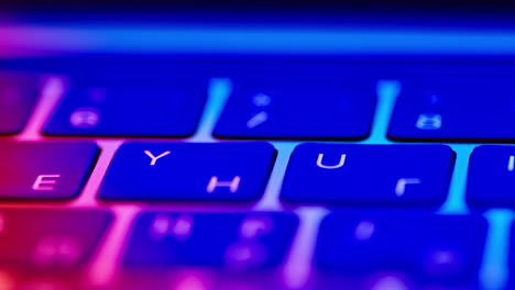 Macro-travel-across-the-keys-on-a-laptop-keyboard-under-a-multicolored-neon-glow