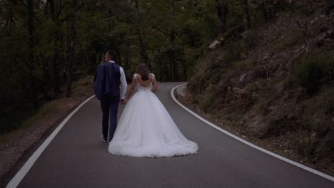 Bride-and-Groom-newlyweds-walking-in-slow-motion-in-the-middle-of-asphalt-forest-road