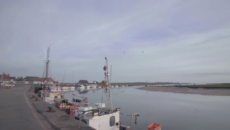 Walking-by-the-dock-in-Wells-where-fishing-boats-wait-for-the-high-tide,-slowmo