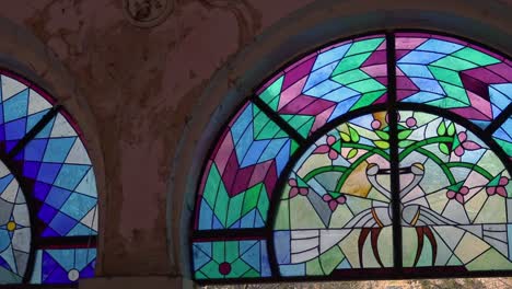 Mysterious-birds-on-stained-glass-in-wall-with-peeling-plaster,-Yerevan,-Armenia