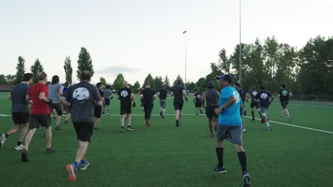 Large-group-of-men-running-and-doing-recreational-activities-on-a-soccer-field-in-the-early-morning