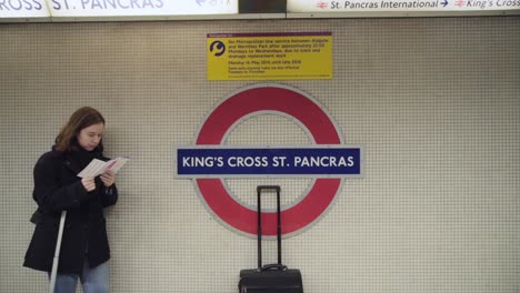 Joven-Mujer-Morena-Caucásica-Con-Chaqueta-De-Pie-Con-Bolsas-De-Equipaje-En-King&#39;s-Cross-St-De-Londres