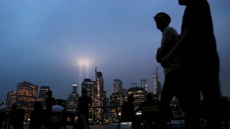 People-walking-in-Brooklyn-Bridge-Park,-Tribute-in-Light-in-Background