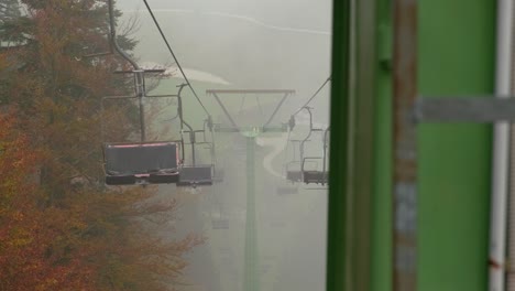 Revealing-shot-of-old-rusty-chair-lift-at-ski-resort-in-summer-fog