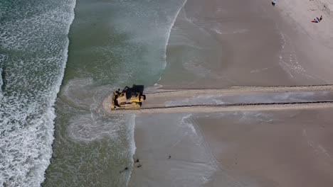 Una-Topadora-De-Oruga-De-Maquinaria-Pesada-Empuja-Un-Pasaje-Para-Que-El-Agua-Fluya-Desde-La-Reserva-Natural-Del-Estuario-De-Zandvlei-Hacia-La-Playa-De-Muizenberg