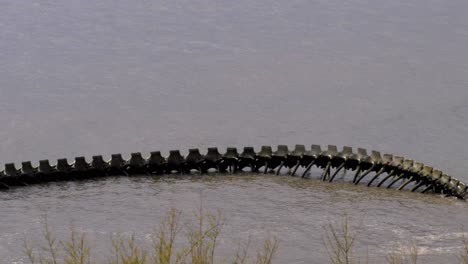 Handheld-pan-of-"Serpent-d'Océan"-at-high-tide,-greenery-in-foreground