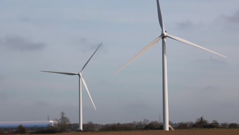 Ein-Paar-Schnell-Drehender-Windräder-Inmitten-Eines-Braunen-Feldes