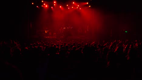 Music-Band-Performing-In-Theater-With-Red-Stage-Lighting-Watched-By-The-Crowd