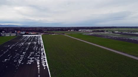 Drohnenaufnahme-Von-Braunen-Und-Grünen-Feldern-Im-Winter-Mit-Wenig-Schnee-Und-Kreisender-Bewegung-Nach-Rechts