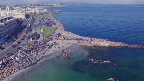 Toma-Aérea-De-Un-Barco-Vikingo-Atracando-Y-Atacando-La-Playa-De-Salthill,-Galway.