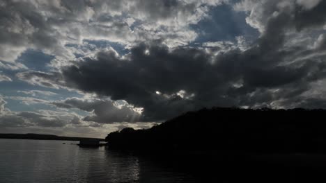 4k-Zeitraffer-Sonnenuntergang-über-See-Und-Kleinem-Berg-Mit-Mehreren-Wolken-Am-Blauen-Himmel