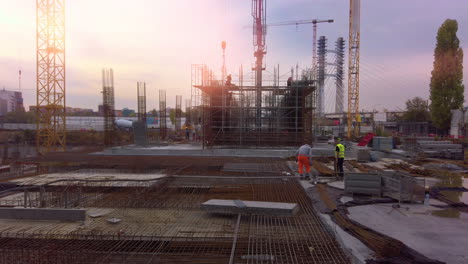 Construction-site-at-sunset-with-cranes-and-workers