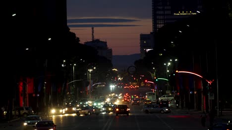 Skyline-Von-Tirana,-Der-Hauptstadt-Albaniens,-In-Der-Dämmerung-Mit-Autos,-Die-Auf-Dem-Boulevard-Fahren