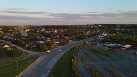 Aerial-view-of-sunlit-houses-and-cars-on-road-Р05,-during-golden-hour,-in-Shepetivka-village,-on-the-countryside-of-Ukraine---pan,-drone-shot