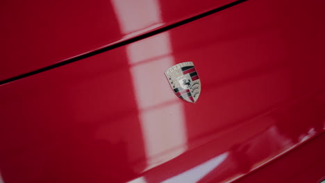 Nahaufnahme-Eines-Roten-Porsche-Autos-Mit-Dem-Ikonischen-Porsche-Emblem-Deutlich-Sichtbar-Auf-Der-Motorhaube