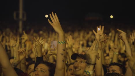 Gente-Viendo-Un-Concierto-En-Vivo,-Levantando-La-Mano-Durante-La-Actuación-En-El-Escenario-Por-La-Noche-En-El-Escenario-Budweiser.