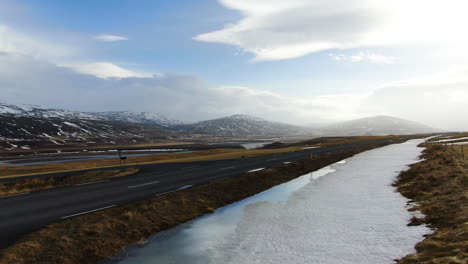 Atemberaubende-Luftaufnahme-Einer-Landschaft-Mit-Blick-Auf-Die-Berge,-Die-Straße-Und-Den-Blauen-Himmel