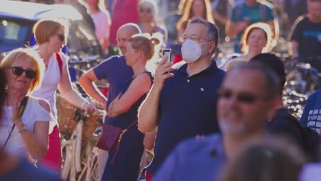 Mann-Mit-Maske-Hält-Ein-IPhone-In-Der-Hand,-Während-Er-Die-Feierlichkeiten-Zum-Tag-Der-Slowenischen-Staatlichkeit-In-Ljubljana,-Slowenien,-Verfolgt