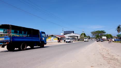 The-main-highway-on-a-dry-dusty-day-with-traffic-and-shops-in-Buka-town-on-remote-tropical-island-of-Autonomous-Region-of-Bougainville,-Papua-New-Guinea