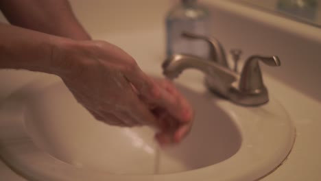 Man-carefully-washing-his-hands-with-soap-and-hot-water-in-a-sink-to-prevent-the-spread-of-virus-or-other-illnesses---isolated-close-up