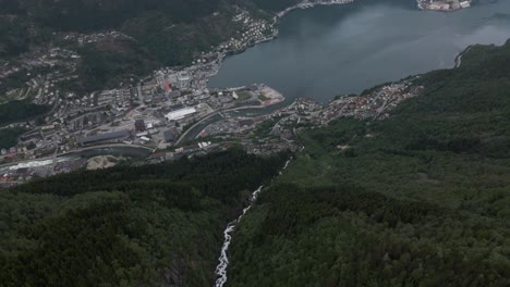 Drone-video-of-a-waterfall-with-the-city-Odda-located-deep-inside-the-fjords-of-Hardanger,-Norway