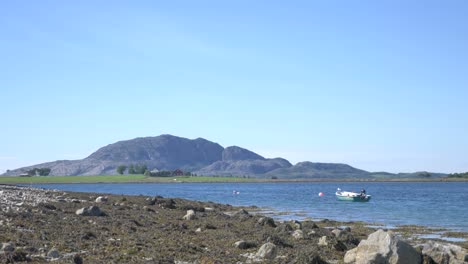 Idyllic-Norwegian-summer-scenery-with-boat,-sea-and-mountain-with-blue-skies