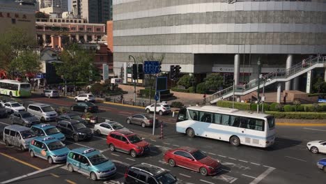 Intersection-in-Pudong,-Shanghai,-China,-tracking-white-bus,-panning-shot