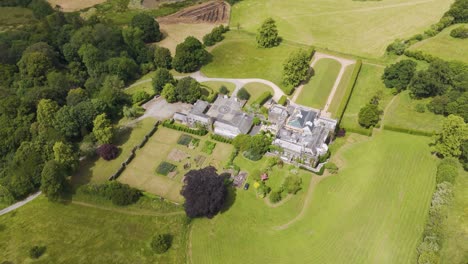 Flyover-view-of-Grade-Two-Star-listed-Hayne-Manor-estate-in-Devon,-UK,-June-2024,-showcasing-the-historic-property-and-surrounding-landscape