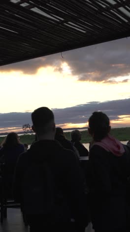 Gente-Mirando-La-Hora-Dorada-Del-Atardecer,-Sol-Entre-Nubes,-Video-Vertical