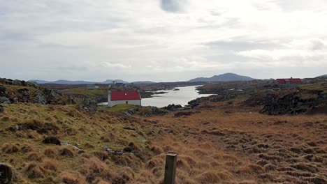 Houses-in-rural-countryside-overlooking-lake-loch-of-water-on-remote-islands-of-Outer-Hebrides-in-Scotland-UK