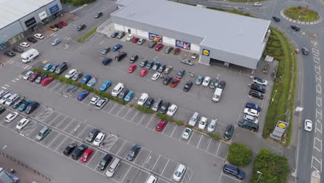 Drone-orbital-view-of-Lidl-supermarket-with-surrounding-carpark-and-nearby-roads,-Bude,-Cornwall,-UK,-July-2024