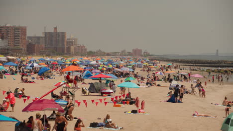 Coney-Island-beach-during-summer,-people-relaxing-on-the-sand-in-New-York,-USA