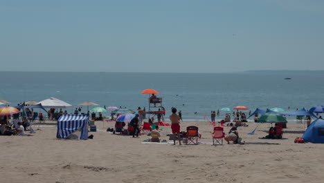 Playa-Llena-De-Gente-Relajándose-En-La-Suave-Arena-De-Coney-Island,-Nueva-York,-EE.UU.