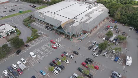 Aerial-rising-view-of-Morrisons-supermarket-with-adjacent-carpark-and-surrounding-area,-Bude,-Cornwall,-UK,-July-2024