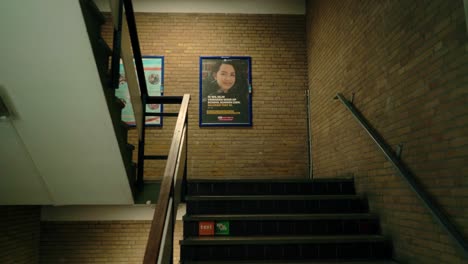 Interior-shot-of-a-high-school-corridor-with-stairs-and-advertisements-on-brick-walls